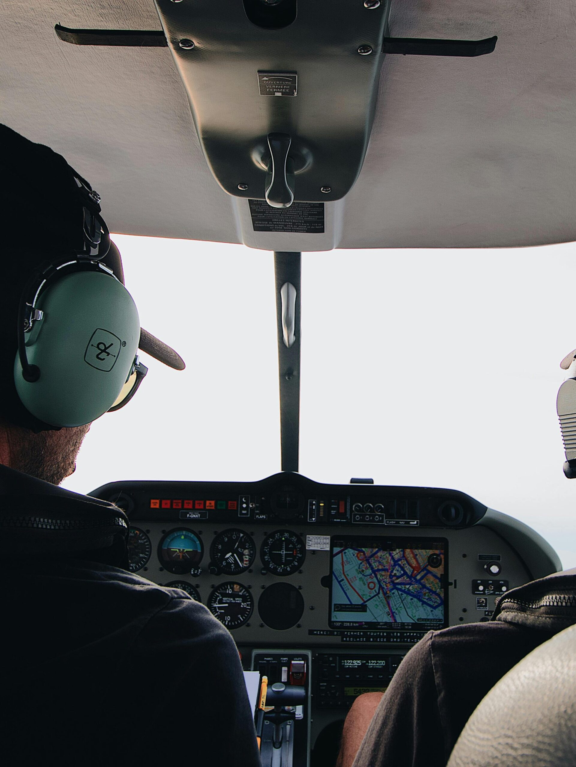 Two pilots with headsets operating controls in an aircraft cockpit.